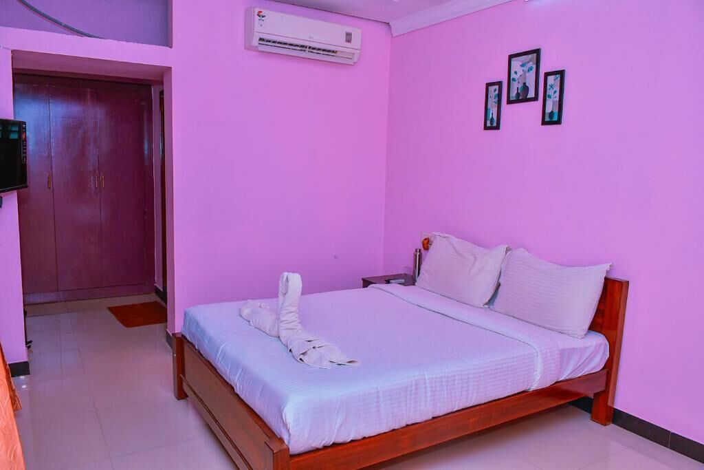 Un dormitorio con cama, aire acondicionado, una puerta y televisor montado en la pared.