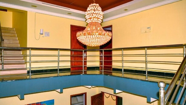 A multi-level interior with a staircase, a chandelier, and a painting. -  Coral Shelters Service Apartments Pykara (Pykara)
