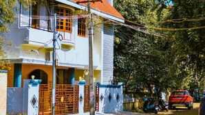 A two-story house with a balcony, a gated entrance, and a parked car. -  Coral Shelters Service Apartments Pykara (Pykara)