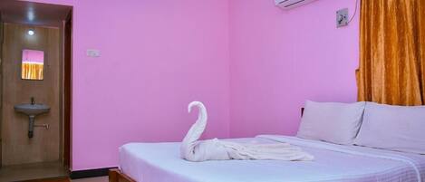 Un dormitorio con una cama, una toalla en forma de cisne blanco, un equipo de aire acondicionado y una puerta de madera.