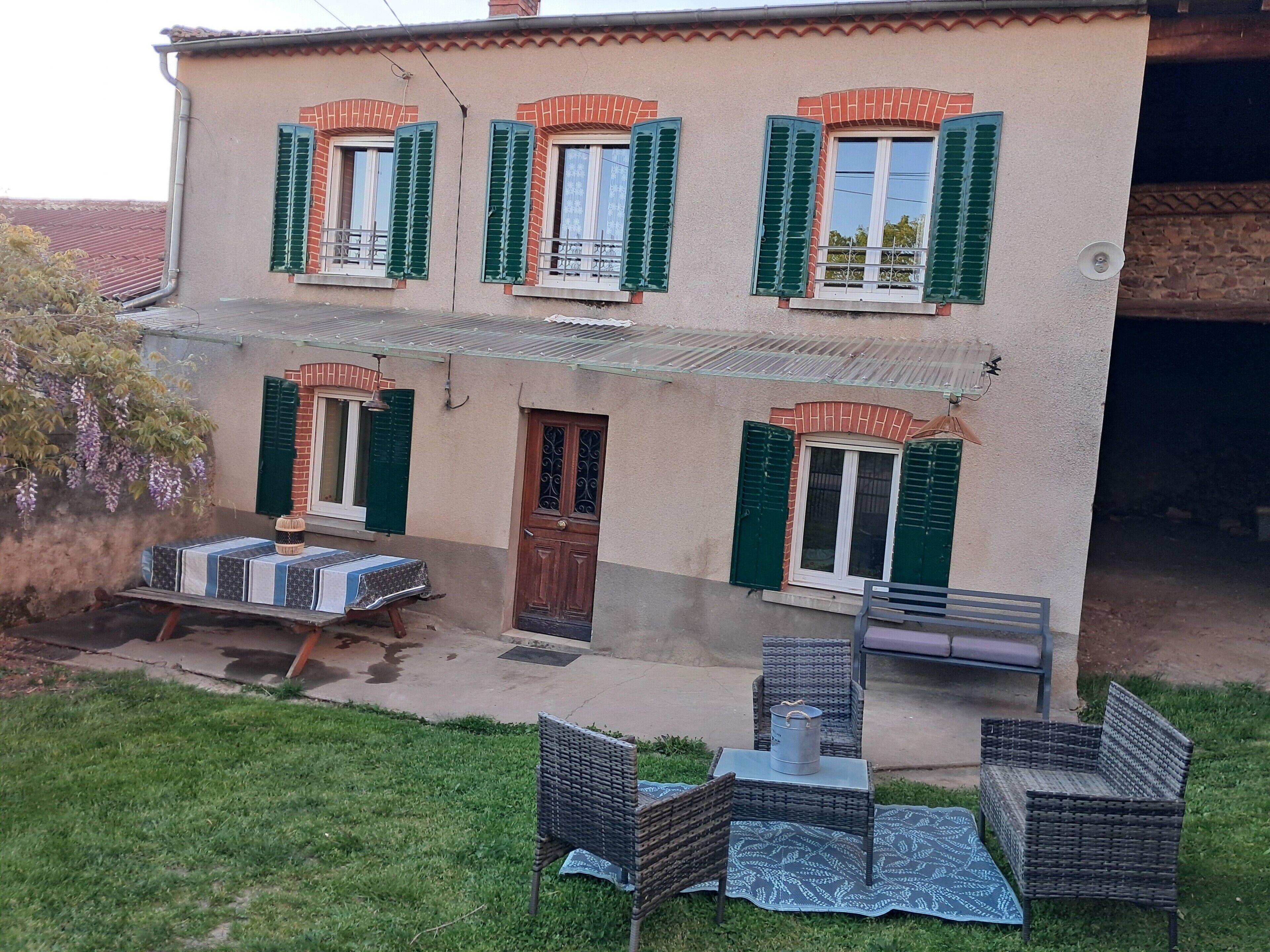 Une maison à deux étages avec un balcon, une porte et une fenêtre équipée de volets.
