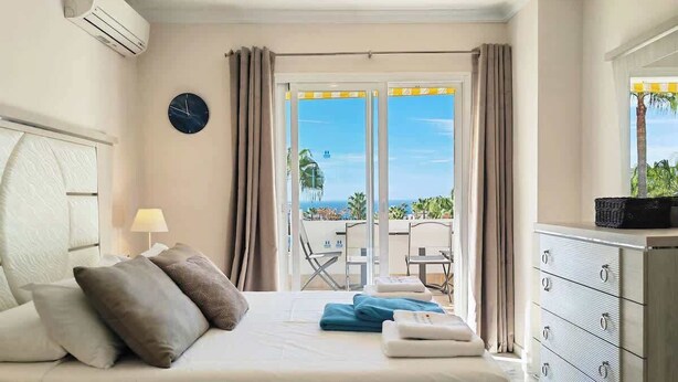A hotel room with a bed, a dresser, a desk, a chair, a lamp, and a view of the ocean. - Sea view * Rooftop Terrace * Pool + Bar *Top Floor (Málaga)