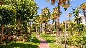 A pathway lined with palm trees and greenery, leading to a building with a white facade. - Sea view * Rooftop Terrace * Pool + Bar *Top Floor (Málaga)
