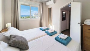 A hotel room with two beds, a window with a view, a door leading to another room, and a small table with a lamp. - Sea view * Rooftop Terrace * Pool + Bar *Top Floor (Málaga)