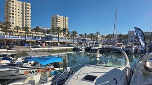 Een jachthaven met verschillende boten die aanmeren, een heldere lucht en gebouwen op de achtergrond.