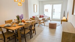 Een moderne woonkamer met een eethoek, met een bank, salontafel en een eettafel gedekt met borden en glazen.