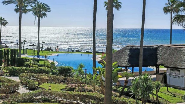 Ein Resort mit Swimmingpool, Palmen und Meerblick.
