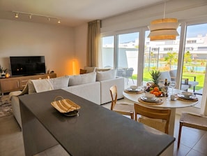 Una sala de estar moderna con sofá, mesa de comedor y televisor.