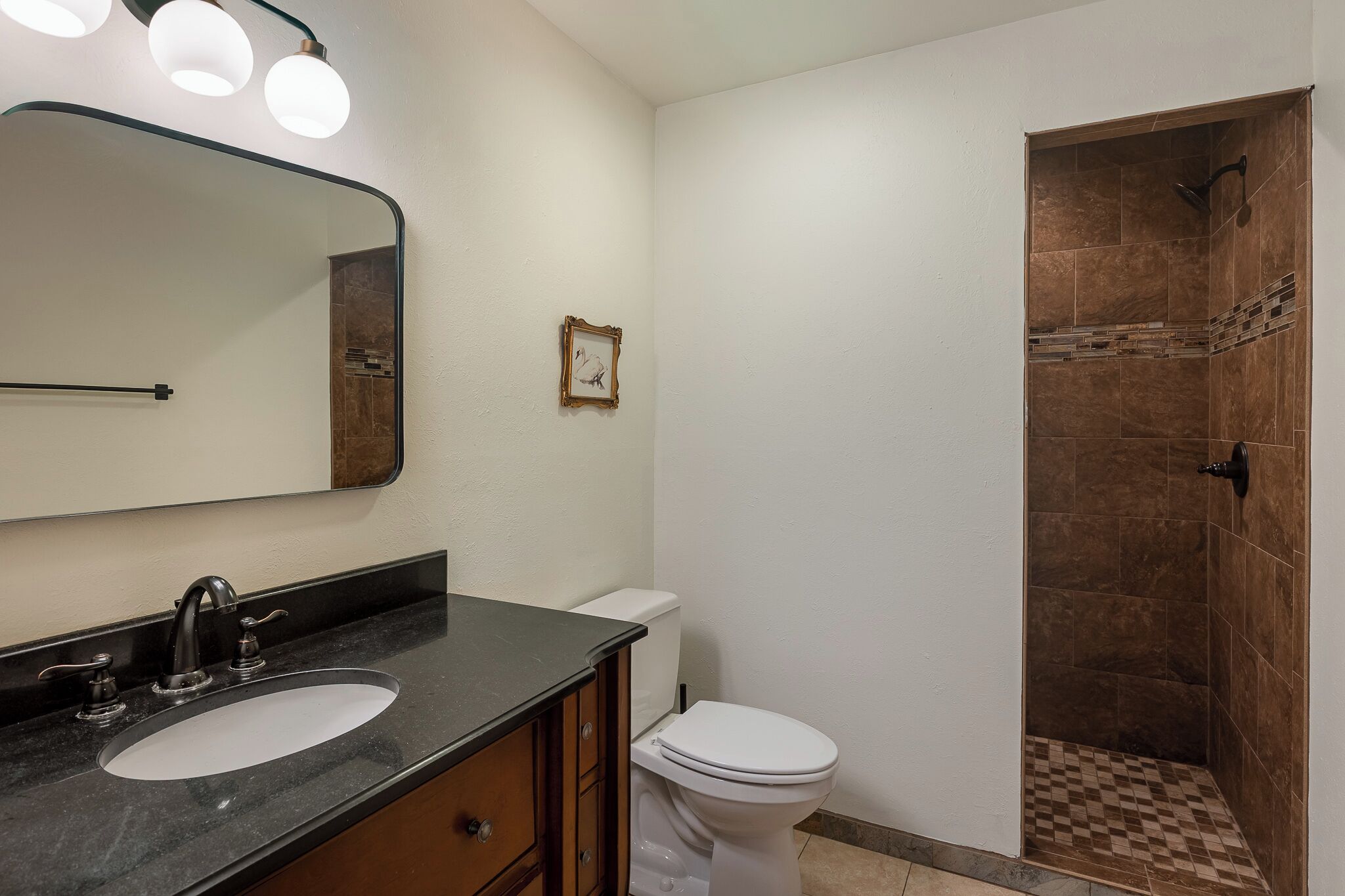 Une salle de bain équipée d’un lavabo, d’un miroir, de toilettes et d’une douche.