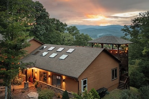 A two-story house with a sloped roof, multiple skylights, and a wooden deck.