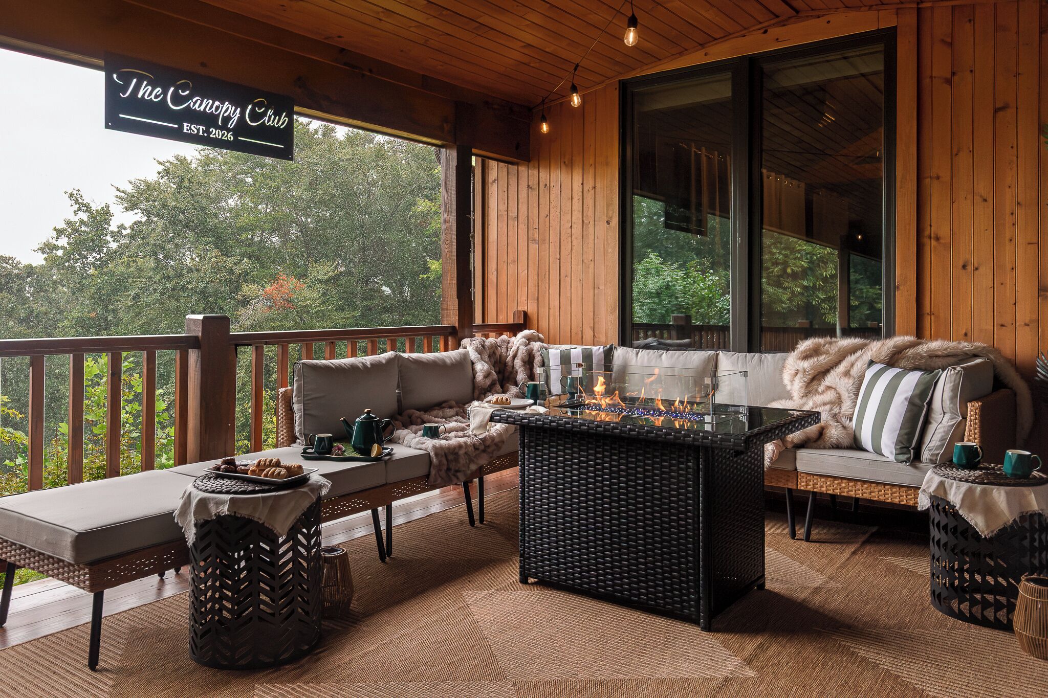 Un espace extérieur accueillant, aménagé avec un long banc, un canapé confortable et une petite table agrémentée d’un foyer.