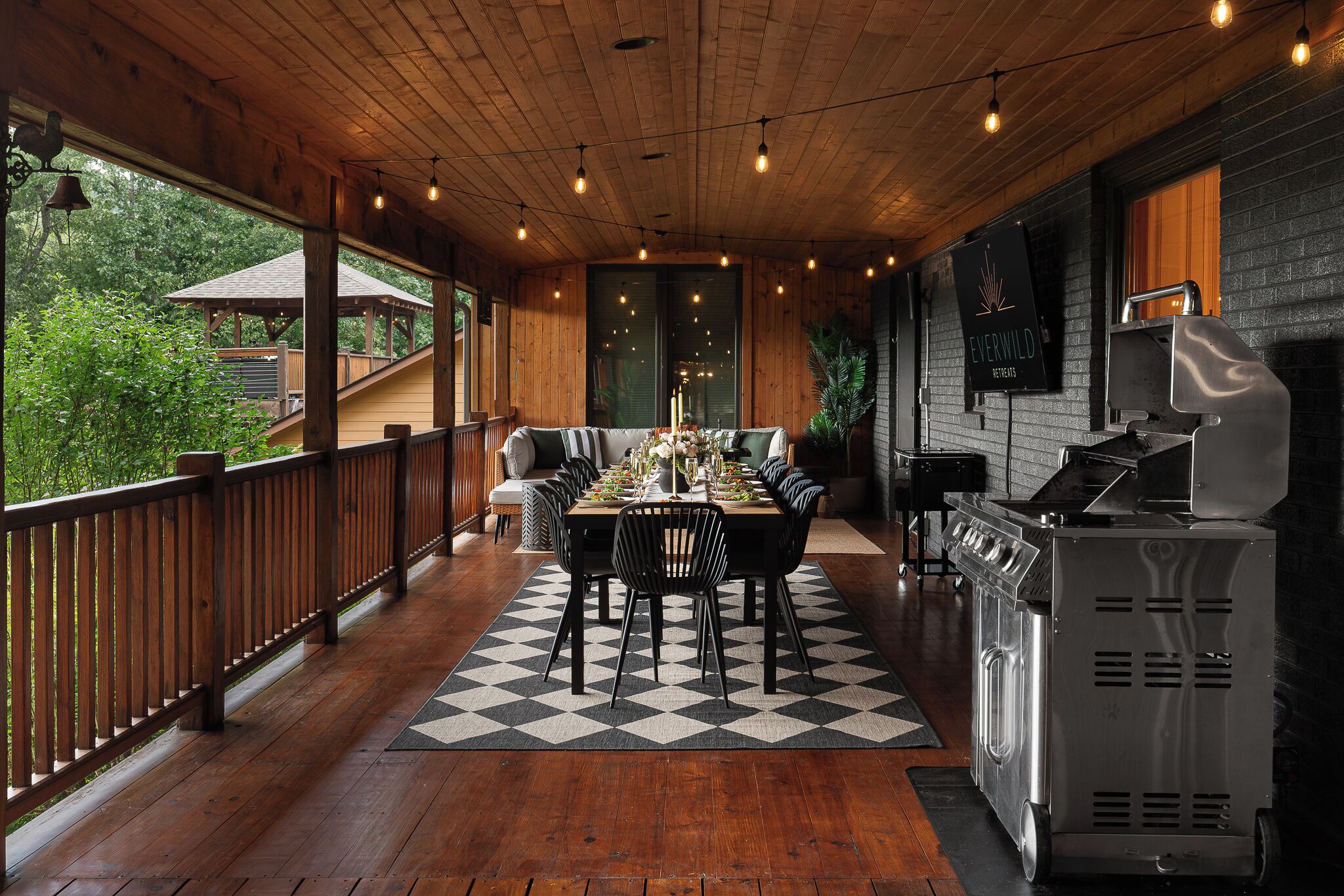 Un espace extérieur abrité, idéal pour prendre ses repas, avec une terrasse en bois, une table à manger pour quatre personnes et un coin barbecue.