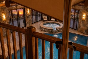 Ein Whirlpool, umgeben von Steinmauern, einem Holzboden und einem Schwimmbecken.