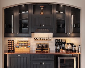 Una cocina con armarios oscuros, una barra de café y diversos equipos para prepararlo.