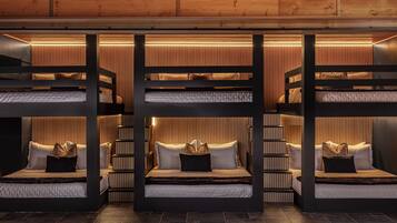 A multi-level bunk bed room with built-in lighting and a wooden ceiling.