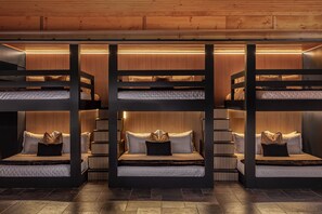 A multi-level bunk bed room with built-in lighting and a wooden ceiling.