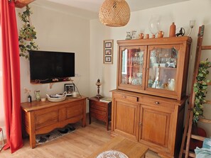 A living room with a TV, wooden cabinet, and a red curtain. - Between the vineyards and the canal. Fully renovated 3-story house (Azille)