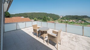 Un balcón con mobiliario de mimbre y vistas a un río y colinas.