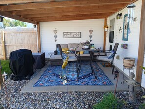A covered patio with a seating area, a table, and a barbecue grill. - Cozy 2-bedroom house in welcoming Elizabethtown (Elizabethtown)