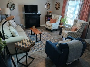 A living room with a sofa, chairs, a coffee table, a fireplace, a television, and decorative items. - Cozy 2-bedroom house in welcoming Elizabethtown (Elizabethtown)