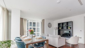 Ett modernt vardagsrum med en matplats, en soffa, en tv och en klocka på väggen.