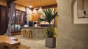 Eine moderne Küche mit Backsteinwand, Holzschemeln, einer großen Topfpflanze und Pendelleuchten.