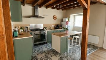 A kitchen with wooden beams, green cabinets, a tiled floor, and a window.