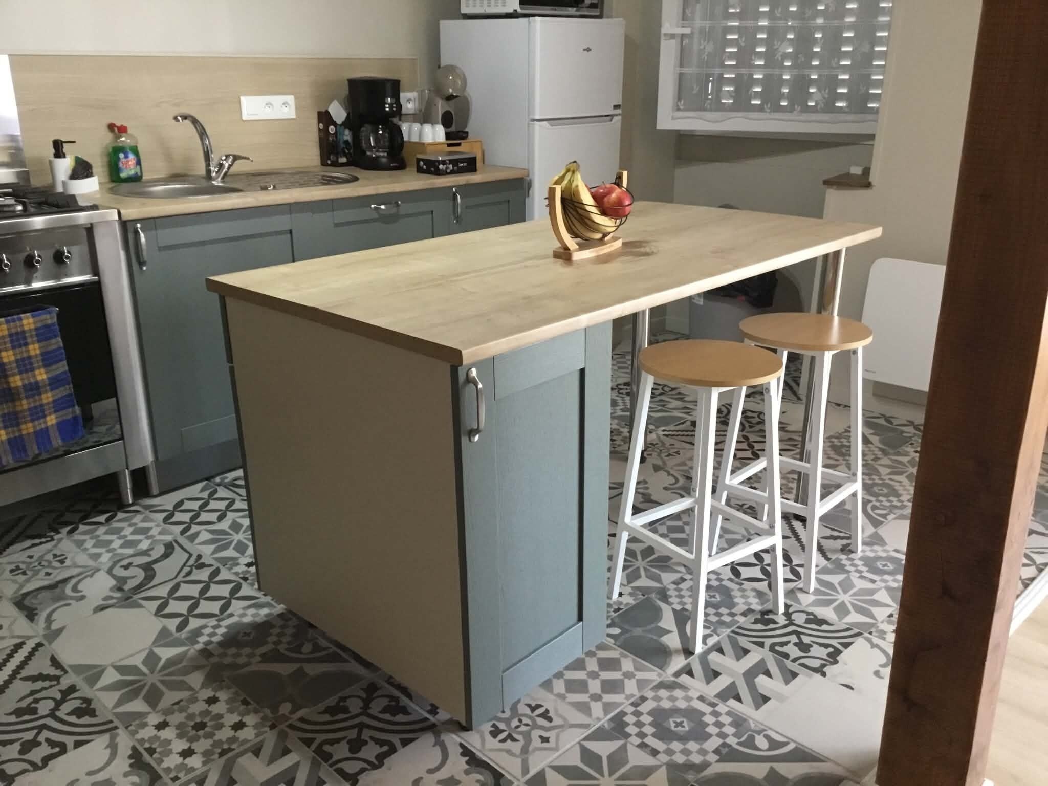 A kitchen with a central island, bar stools, a stove, and a patterned floor.