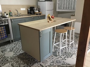 Una cocina con una isla central, taburetes de bar, estufa y piso estampado.