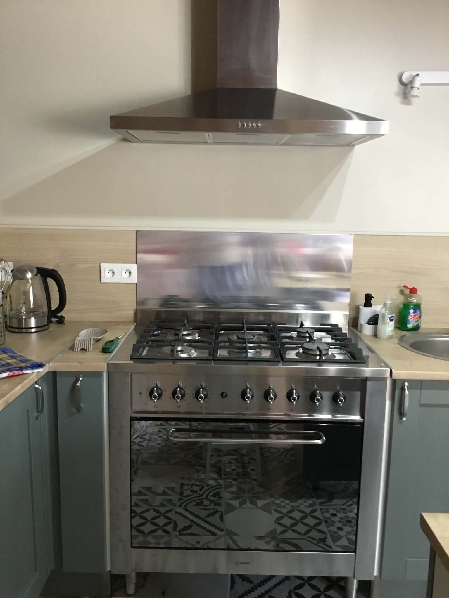 Een keuken met een roestvrijstalen fornuis, oven en afzuigkap.