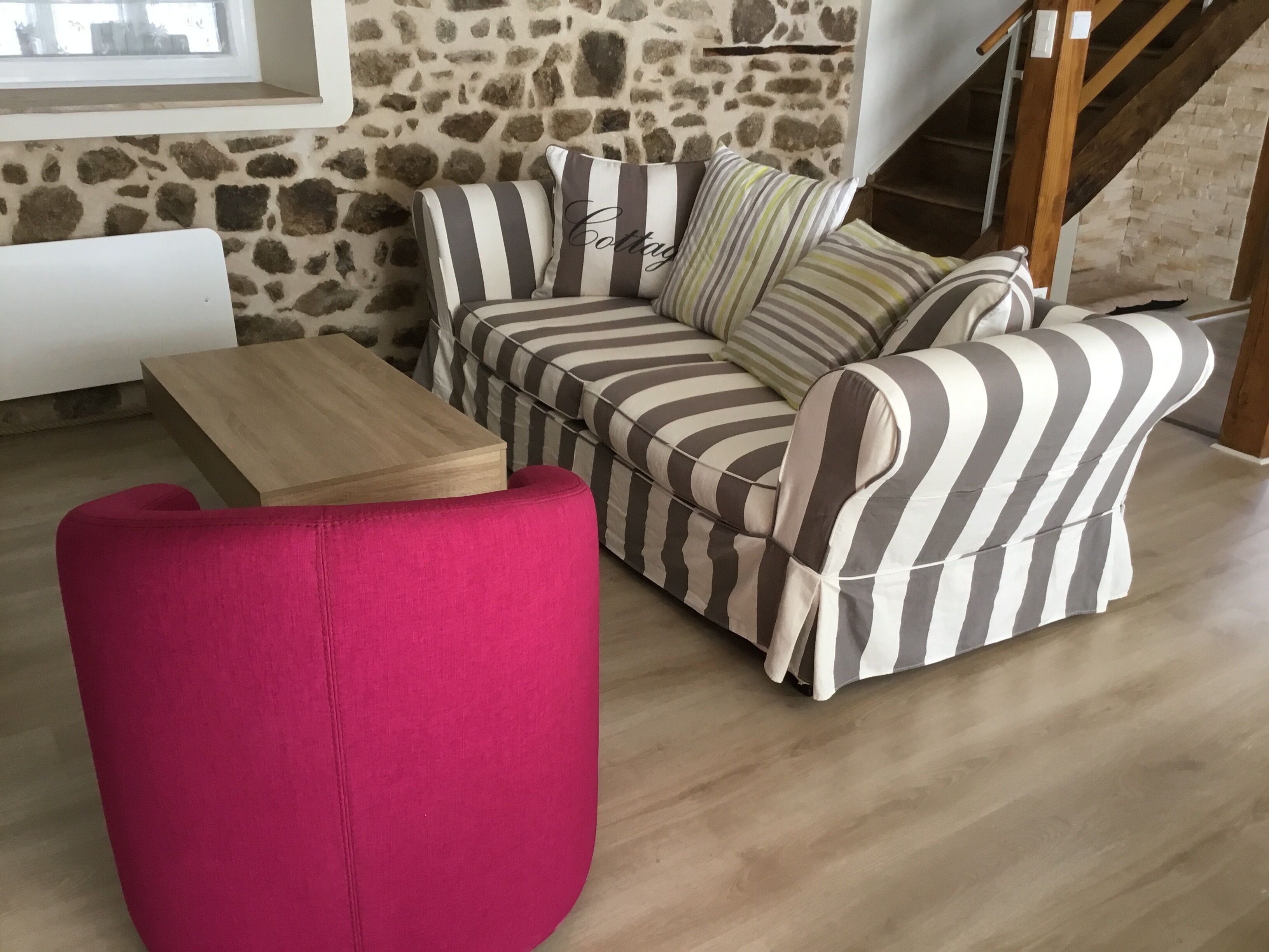 A living room with a striped sofa, a wooden coffee table, and a red chair.