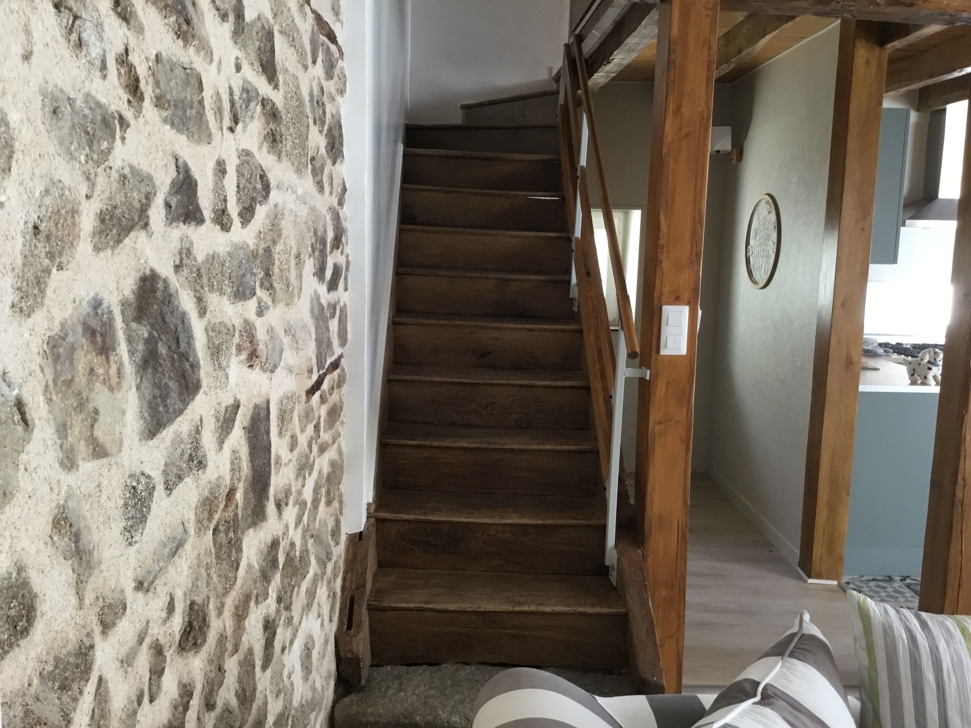 A staircase with a stone wall on one side and a wooden railing.