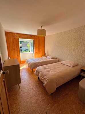 A room with two beds, a wooden floor, a patterned wall, and a window with a view of greenery. - 🏡 The Heron's Cozy Little Nest | Sleeps 6–7 | Pets welcome (Felletin)