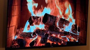 A flat-screen TV mounted on a wall with a fire image displayed. - Hotel NIRA (Sofia)