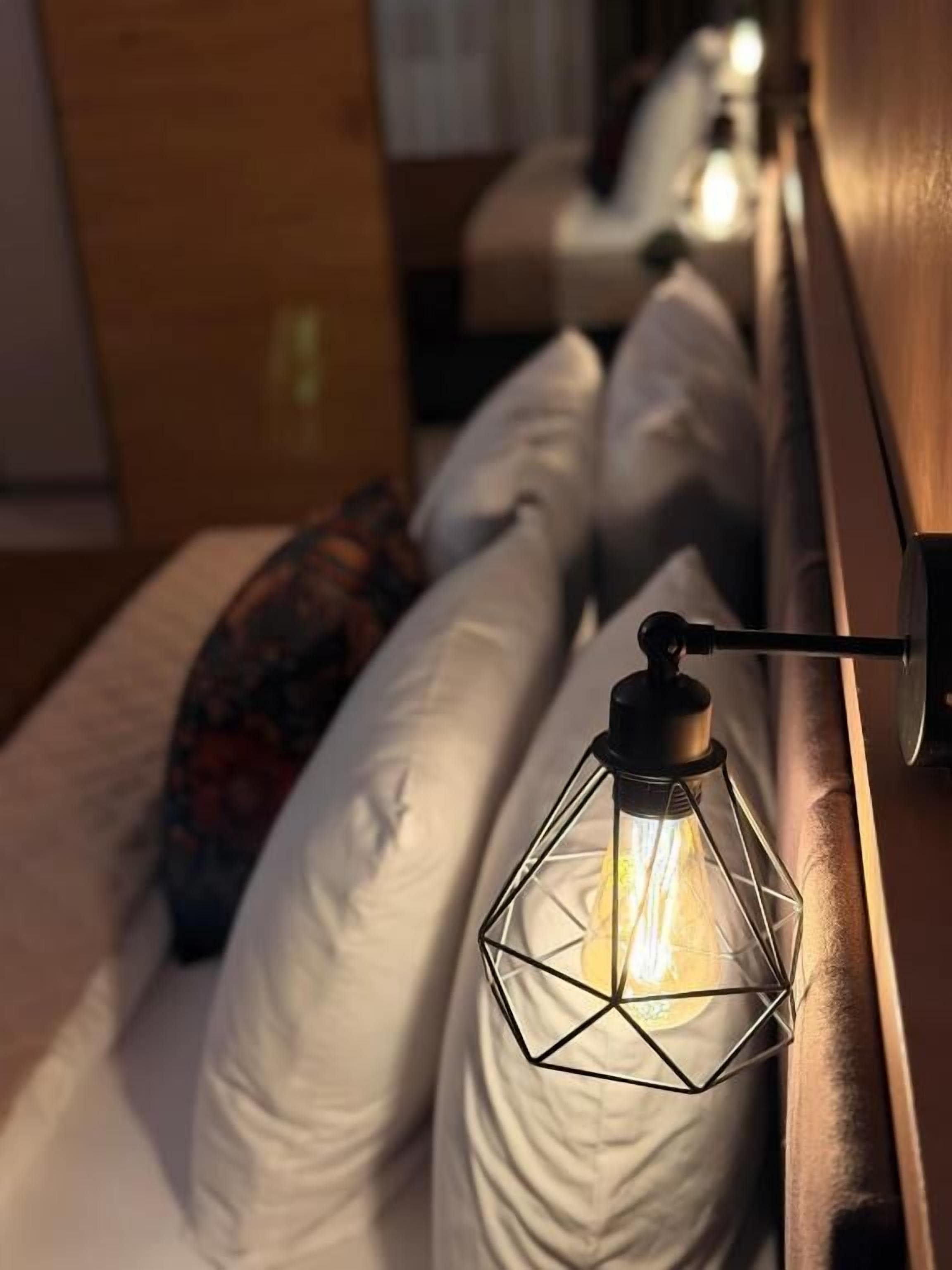 Een bed met witte kussens en een hanglamp.