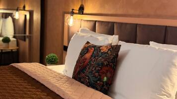 A neatly made bed with a quilted brown cover, a decorative pillow with a floral pattern, and a headboard with a light fixture.