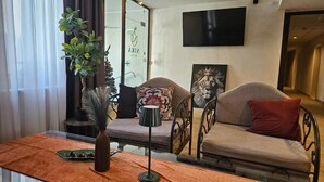 A modern hotel room with a sofa, decorative pillows, a vase, and a television mounted on the wall. - Hotel NIRA (Sofia)
