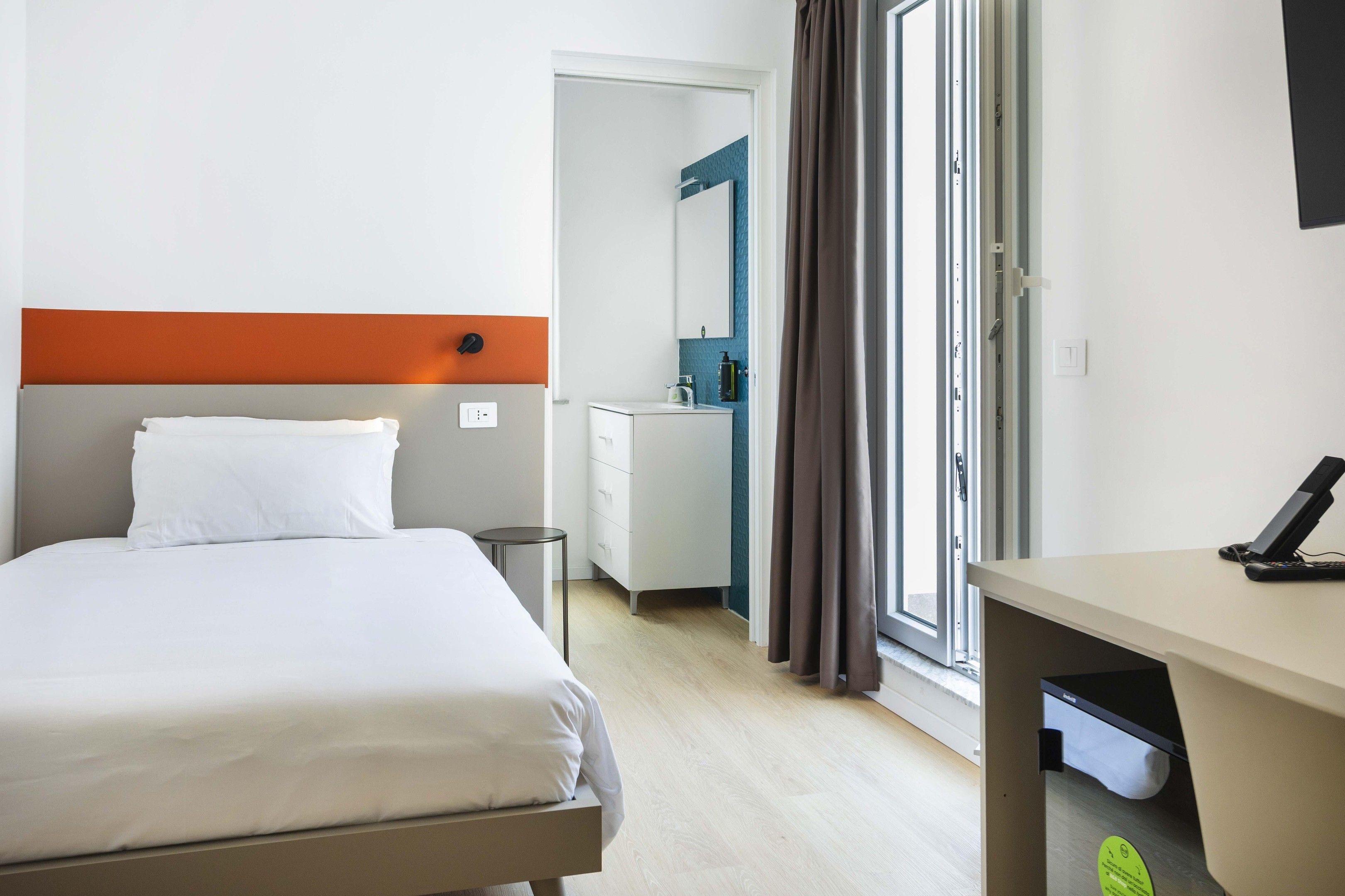 Una habitación de hotel con cama, escritorio, baño y vistas por la ventana.