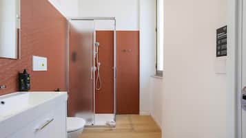 Ein Badezimmer mit Dusche, Toilette und Waschbecken mit einer Seifenflasche.