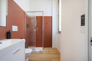 Un baño con ducha, inodoro y lavamanos con una botella de jabón.
