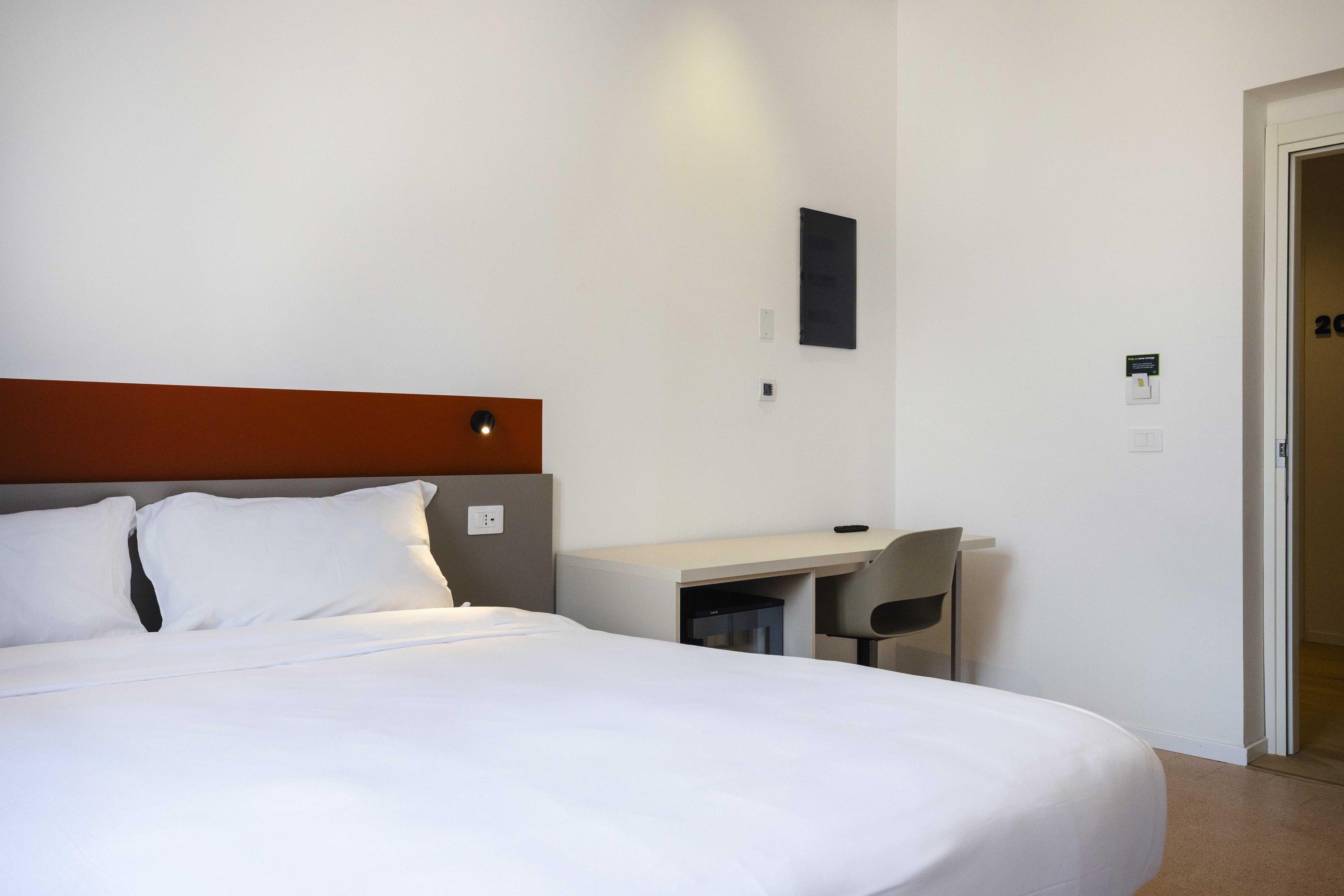 A hotel room with a bed, a desk, and a chair.