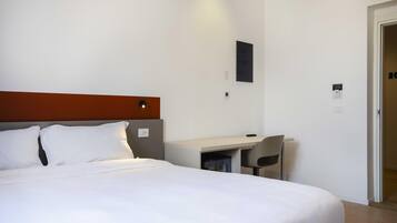 A hotel room with a bed, a desk, and a chair.