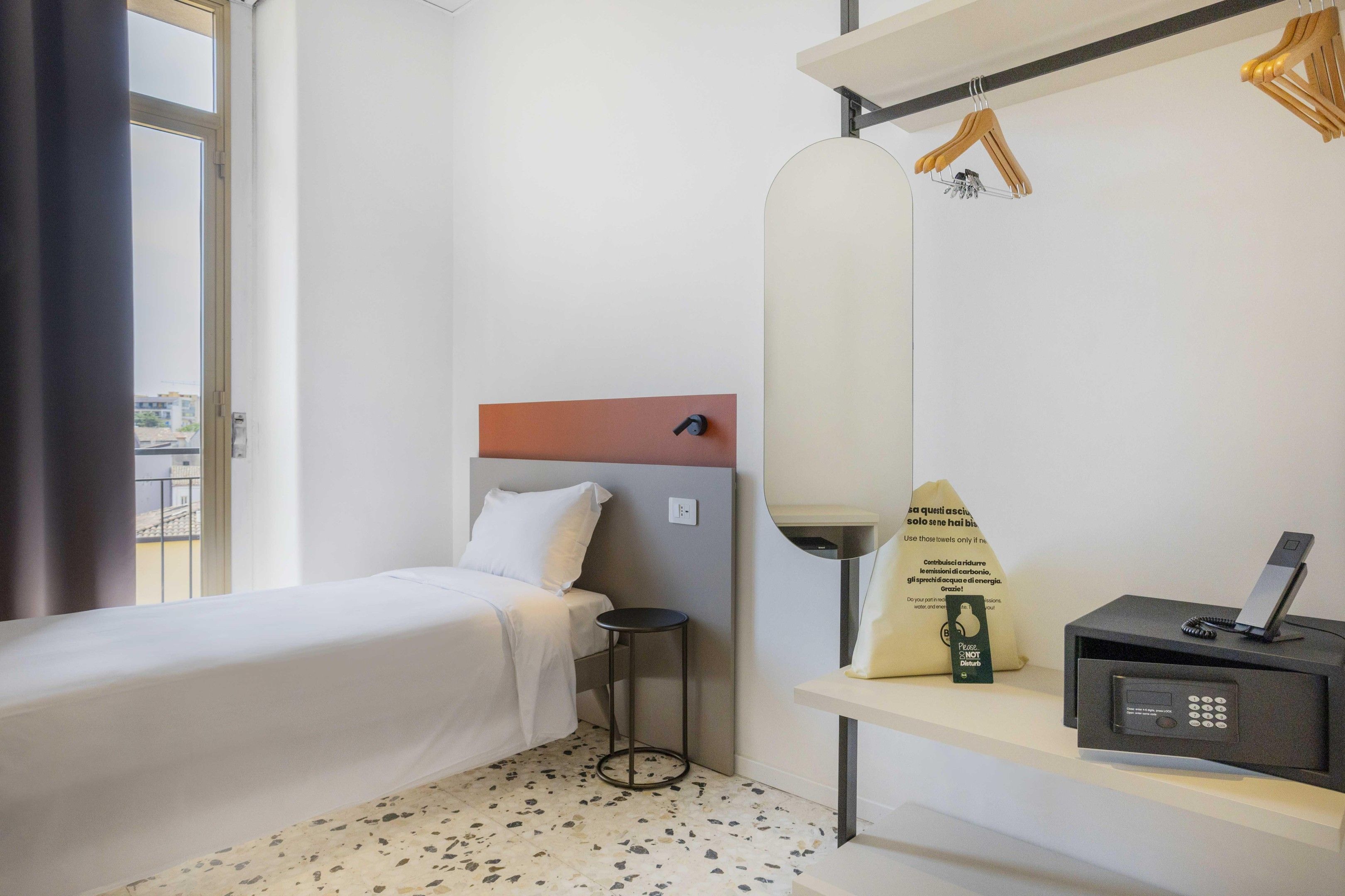 Una habitación de hotel con una cama, una mesita, un espejo y un escritorio con un teléfono.