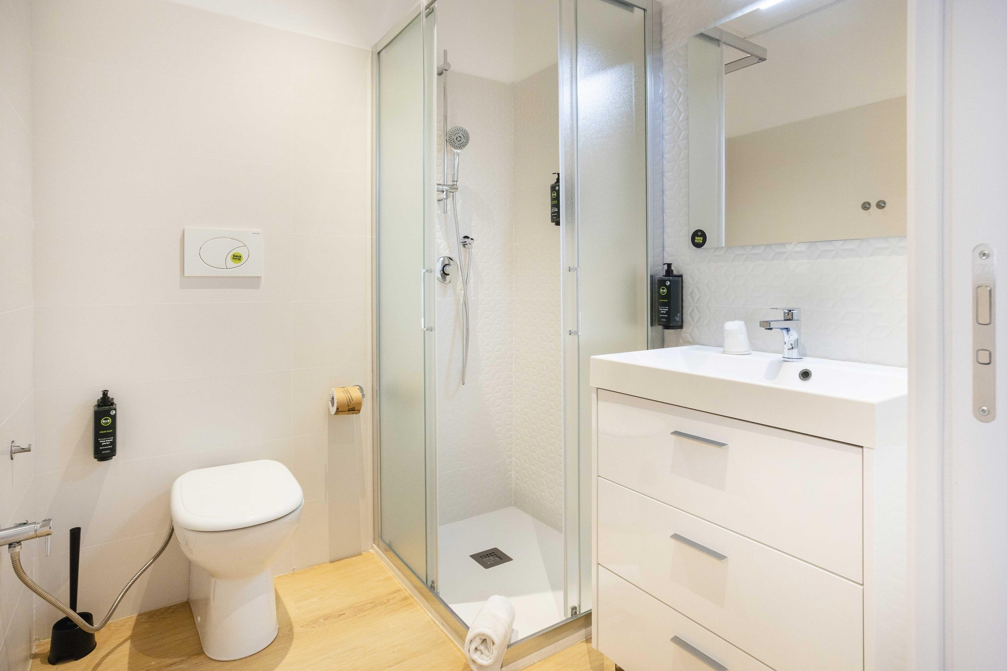 Un bagno moderno con doccia vetro, water bianco e mobile lavabo con specchio.