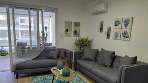 Een moderne woonkamer met twee grijze banken, een tapijt met een patroon en wanddecoratie.