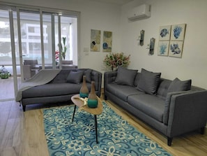 Ein modernes Wohnzimmer mit zwei grauen Sofas, einem gemusterten Teppich und Wandbildern.