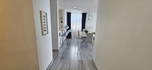 Una cocina moderna con encimera de mármol, lámpara colgante y comedor con mesa y sillas blancas.
