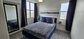 Un dormitorio con cama, vistas a la ciudad, un cuadro y una planta.