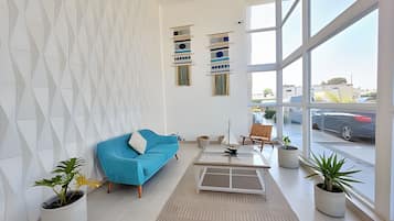 Uma sala de estar moderna com um sofá azul, uma mesa de centro e plantas em vasos.