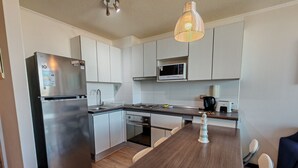 A modern kitchen with stainless steel appliances, white cabinetry, a wooden island, and a hanging pendant light.